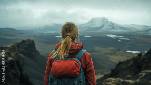 Girl hiking up hill in dramatic mountain landscape from behind. photo