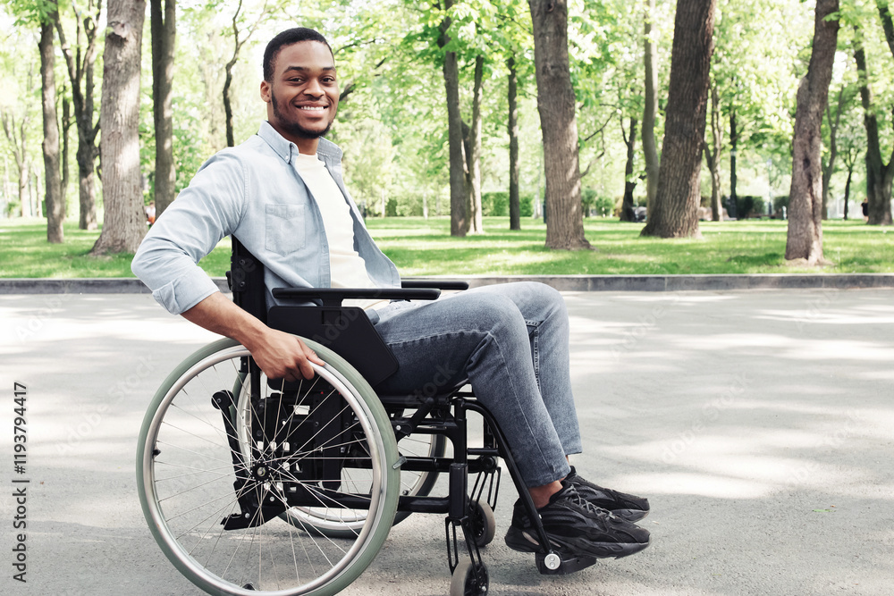 Happy young black man in wheelchair spending time at city park, smiling at camera, full length. Cheerful millennial African American guy with disability using mobility aid, having walk outdoors Happy young black man in wheelchair spending time at city park, smiling at camera, full length. Cheerful millennial African American guy with disability using mobility aid, having walk outdoors