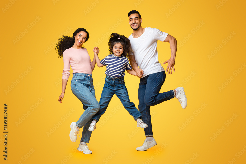 Portrait Of Cheerful Excited Middle Eastern Family Of Three Holding Hands While Jumping In Air Over Yellow Background In Studio, Happy Arab Parents And Little Daughter Having Fun Together, Copy Space Portrait Of Cheerful Excited Middle Eastern Family Of Three Holding Hands While Jumping In Air Over Yellow Background In Studio, Happy Arab Parents And Little Daughter Having Fun Together, Copy Space