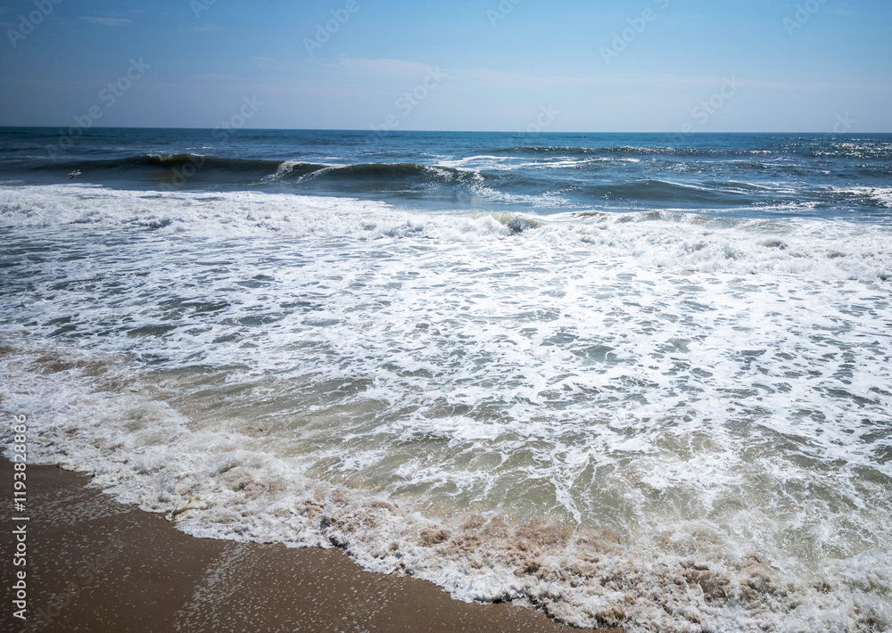 Waves Crashing on Sandy Beach Under Clear Blue Sky During Sunny Day Waves Crashing on Sandy Beach Under Clear Blue Sky During Sunny Day