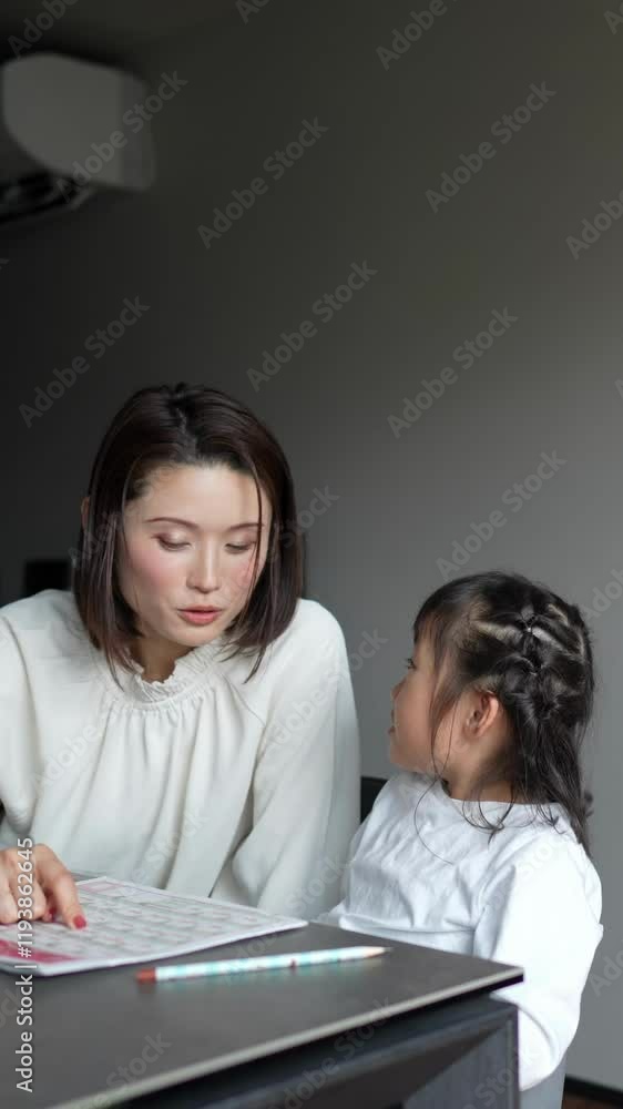 A Japanese parent and child, a woman in her 30s, a man in his 20s, and a 6-year-old girl, are studying English in the living room, wearing simple white clothes. Vertical video. A Japanese parent and child, a woman in her 30s, a man in his 20s, and a 6-year-old girl, are studying English in the living room, wearing simple white clothes. Vertical video.