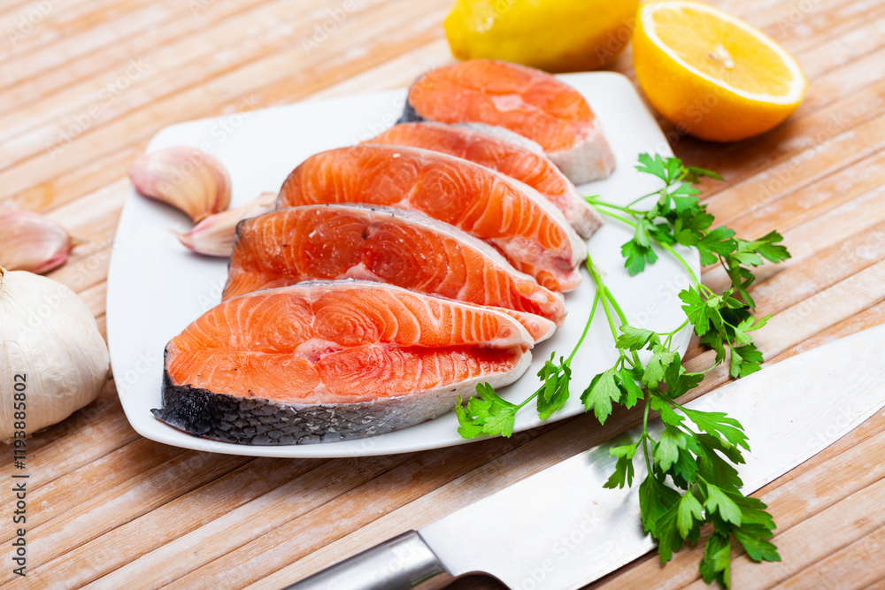 Closeup of fresh organic cutting salmon seafood with herbs and lemon on a table Closeup of fresh organic cutting salmon seafood with herbs and lemon on a table
