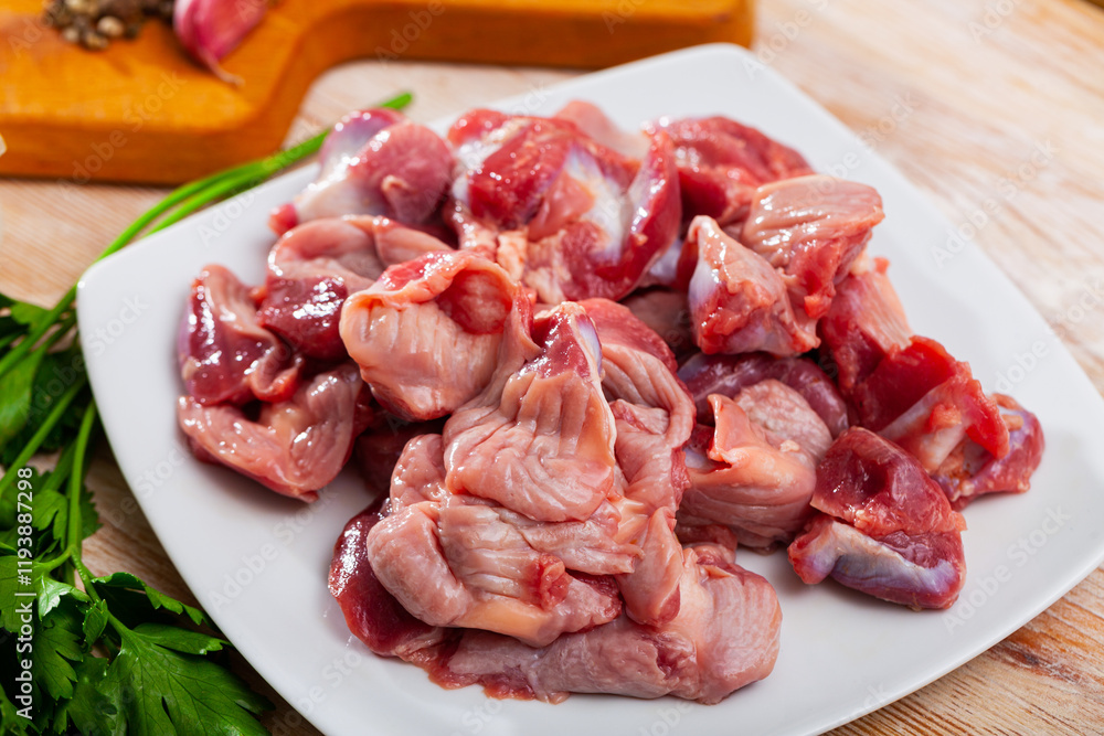 Picture of raw chicken gizzards and greens on wooden surface Picture of raw chicken gizzards and greens on wooden surface