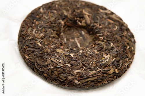 Pressed raw pu-erh tea cake showcasing natural loose-leaf texture and details of aged tea leaves symbolizing craftsmanship tradition in tea preparation, perfect for authentic tea lovers and collectors photo