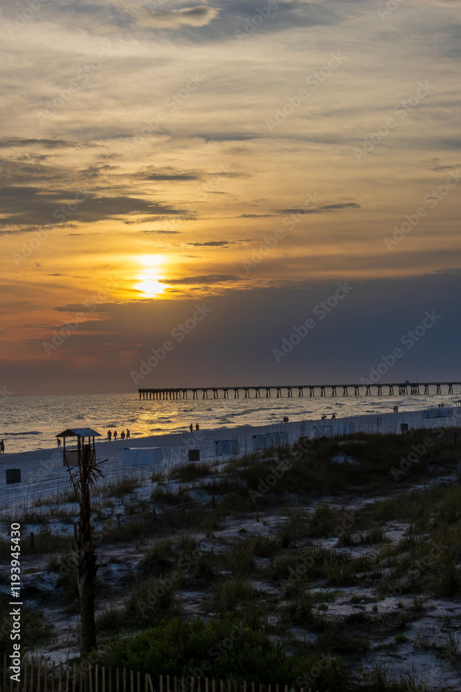 a beautiful sunrise over the Atlantic ocean with Panama City Beach City Pier, people walking, palm trees and waves at Panama City Beach Florida USA a beautiful sunrise over the Atlantic ocean with Panama City Beach City Pier, people walking, palm trees and waves at Panama City Beach Florida USA