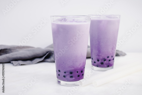 Two Glasses of Purple Sweet Potato Bubble Tea: Ube boba with ice cubes and clear silicone straws on a white background