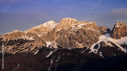 Golden Sunset Over Majestic Snow-Dusted Mountain Peaks with Serene Forested Slopes and Stunning Blue to Purple Sky Transition