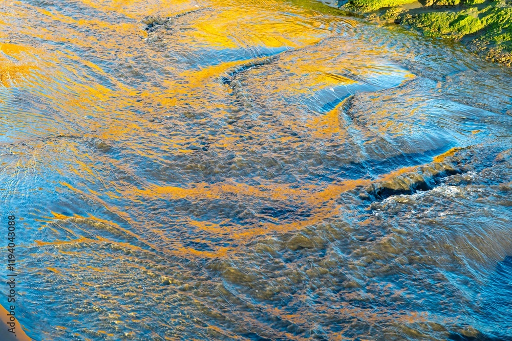 Golden light reflects on rippling water, creating abstract patterns. Nature's beauty. Hamiltons Gap, Awhitu, Auckland, New Zealand Golden light reflects on rippling water, creating abstract patterns. Nature's beauty. Hamiltons Gap, Awhitu, Auckland, New Zealand