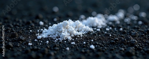 Small white ash fragments scattered on black ground, dirt, tiny specks photo