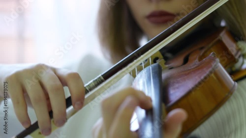 Woman playing violin swiftly with bow, using musical skills. Female fiddler refining music technique, focused classical practice, fast bow strokes, violin mastery with precision, sound performance photo