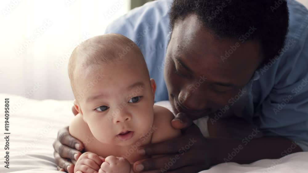 A caring father enjoys a heartfelt moment with his baby at home. The toddler plays on the bed while the dad shows affection. Their bond radiates warmth and love in a cozy atmosphere. A caring father enjoys a heartfelt moment with his baby at home. The toddler plays on the bed while the dad shows affection. Their bond radiates warmth and love in a cozy atmosphere.