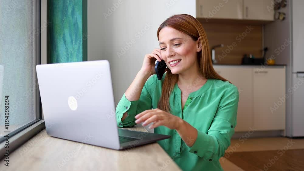 Young woman working online and talking on mobile phone at her home office Young woman working online and talking on mobile phone at her home office