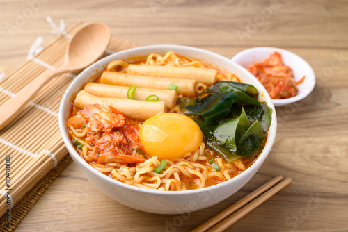 Spicy noodles soup with Tteokbokki, Wakame seaweed and fresh egg yok eating with kimchi cabbage photo