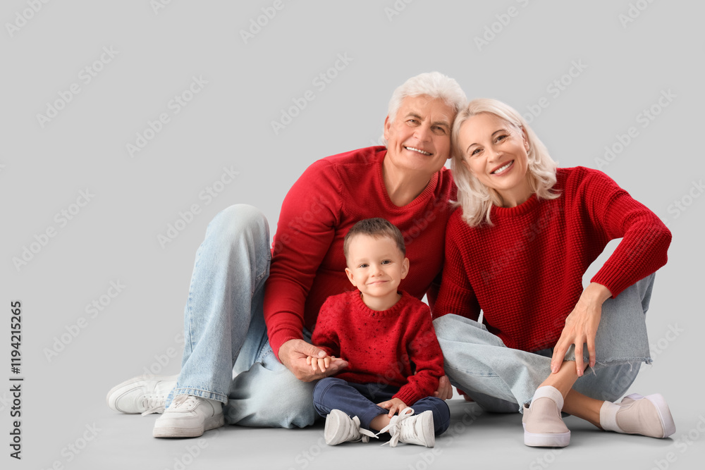 Cute little boy with happy grandparents in warm sweaters on grey background Cute little boy with happy grandparents in warm sweaters on grey background