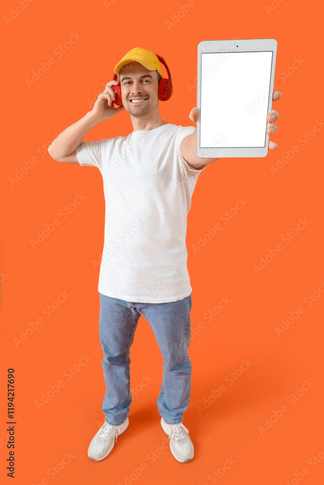 Man with tablet computer and headphones on orange background. Mockup for design Man with tablet computer and headphones on orange background. Mockup for design
