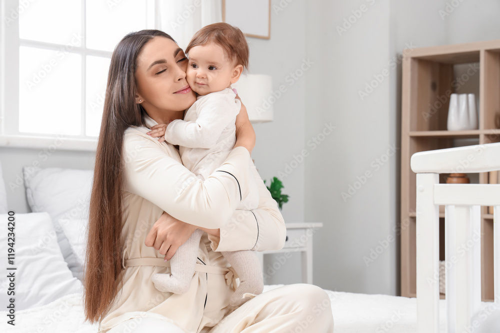 Young mother in pajamas hugging her baby in bedroom. International Hug Day