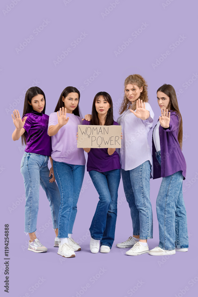 Group of young women holding cardboard with text WOMAN POWER on lilac background Group of young women holding cardboard with text WOMAN POWER on lilac background