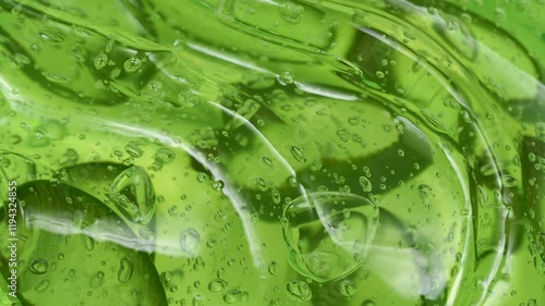 Serum gel texture with aloe vera leaf slices, green transparent cream background