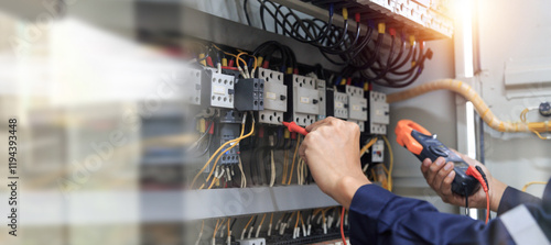 Checking the electrical system, an electrician is using an electric meter to check the electrical system at a control cabinet. for safety
