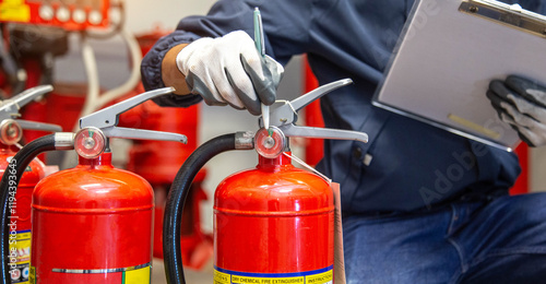 Engineer are checking and inspection a fire extinguishers tank in the fire control room for safety training and fire prevention. photo