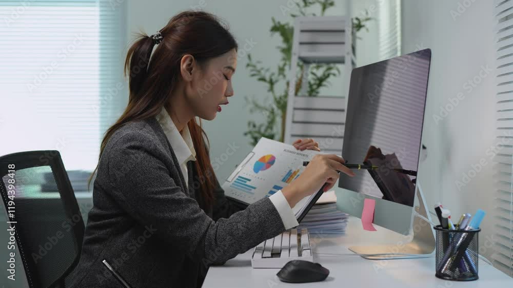 Young professional woman is working with financial documents and using smartphone while sitting at her workplace with computer in modern office. Young professional woman is working with financial documents and using smartphone while sitting at her workplace with computer in modern office.