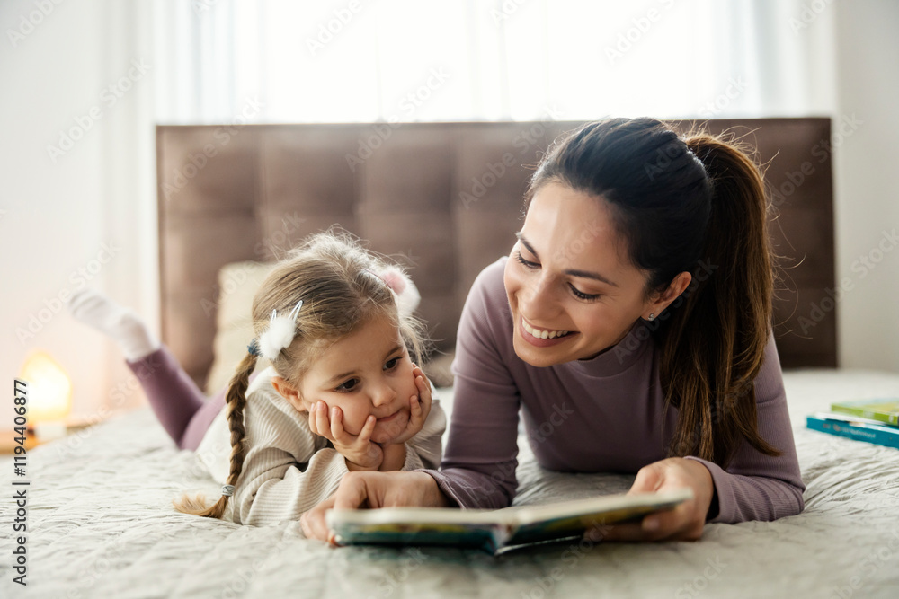 Adorable daughter and mother lying in bed and reading a story form a book at home. Adorable daughter and mother lying in bed and reading a story form a book at home.