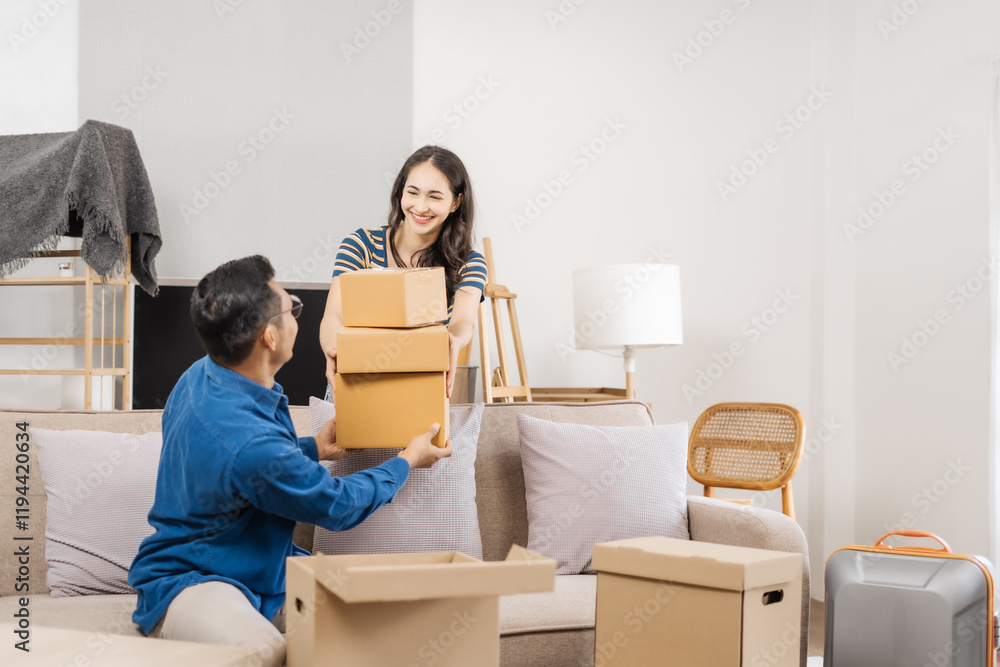Young couple sitting on a sofa, helping each other pack, collecting clothes, putting items in boxes, feeling happy and excited while preparing to move into their new apartment Young couple sitting on a sofa, helping each other pack, collecting clothes, putting items in boxes, feeling happy and excited while preparing to move into their new apartment