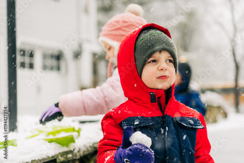 Child in red winter coat holding snowball, playful mood photo