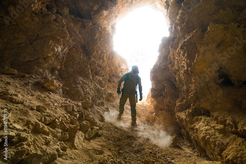 Explorer enters large secret cave, hidden and searching for treasure