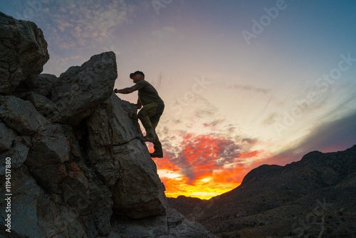 Side view of active person climbing over rocky terrain at daybreak
