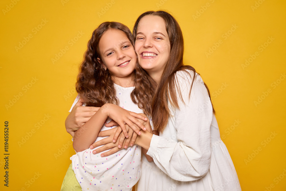 A mother and daughter embrace each other, both smiling widely, with a vibrant yellow backdrop creating a cheerful atmosphere. Their happiness highlights their close bond A mother and daughter embrace each other, both smiling widely, with a vibrant yellow backdrop creating a cheerful atmosphere. Their happiness highlights their close bond
