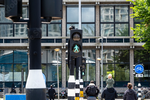 A vibrant green pedestrian signal illuminates a city street, highlighting urban infrastructure and the importance of pedestrian safety in modern city planning. photo