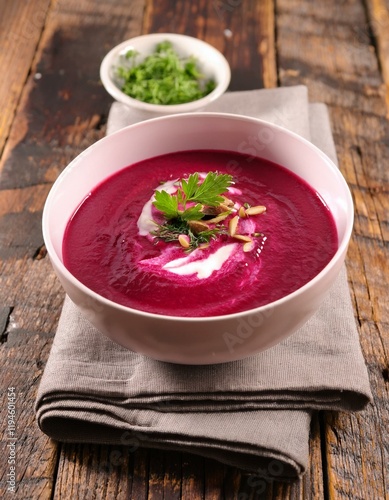 Bowl with hot beetroot cream sopu with green parsley leaves on table with fresh beetroots. Generated image photo