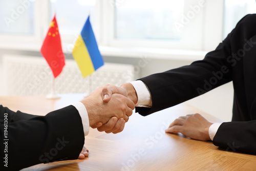 Diplomats shaking hands during meeting at wooden table indoors, closeup photo