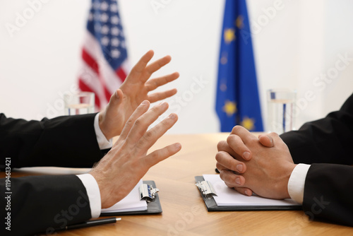 Diplomats negotiating during meeting at wooden table indoors, closeup photo