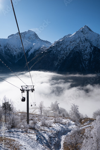 A ski lift over the valley covered with clouds