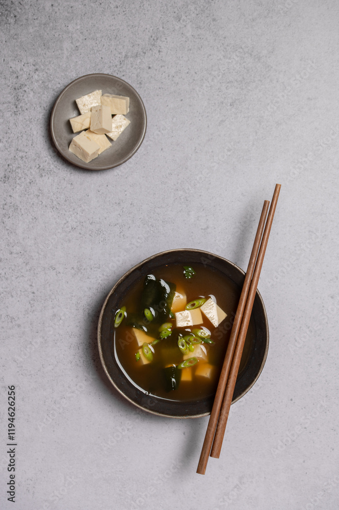 Traditional Japanese Miso soup with Wakame seaweed and tofu cheese with chopsticks for single serving. Vegetarian, vegan and healthy concept. Asian food. Traditional Japanese Miso soup with Wakame seaweed and tofu cheese with chopsticks for single serving. Vegetarian, vegan and healthy concept. Asian food.
