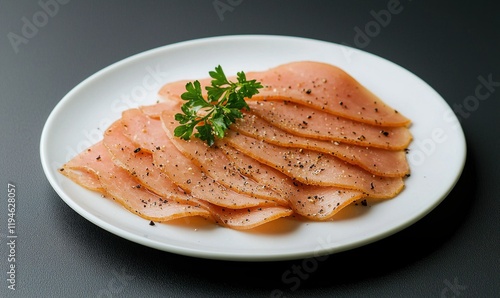 Slices of garlic seasoned salo presented on a white plate with a muted black background photo