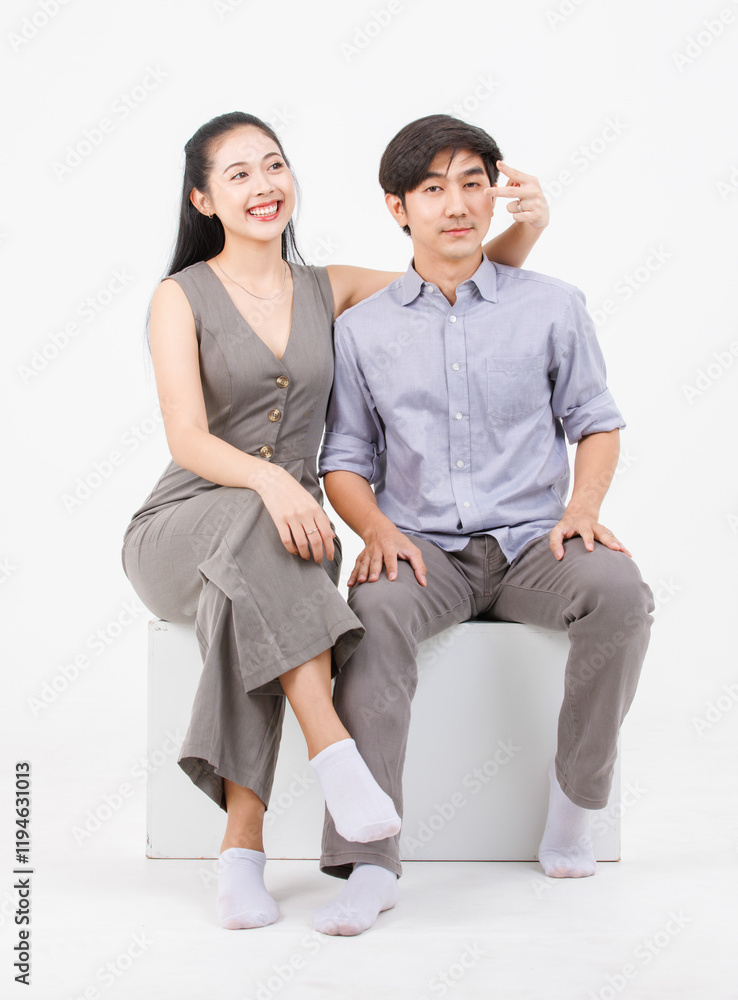 Obraz premium Portrait of lovely young asian happy attractive cheerful couple love, Joyful sweethearts enjoy good time romantic date, sitting on a box posing to camera smiling against together on white background.