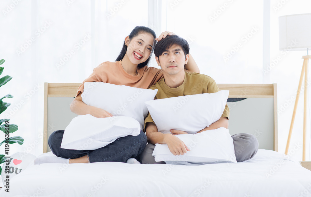 Portrait of young lovely sweet attractive asian happy couple love posing to camera smiling hugging pillow sitting on white bed in bedroom at home good time romantic together Valentine's day concept. Portrait of young lovely sweet attractive asian happy couple love posing to camera smiling hugging pillow sitting on white bed in bedroom at home good time romantic together Valentine's day concept.