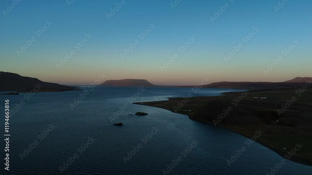 Expansive aerial view of Iceland’s coastline at dusk. The calm waters meet rugged shores, framed by distant mountains and a serene Nordic horizon, capturing the tranquil beauty of untouched Icelandic Expansive aerial view of Iceland’s coastline at dusk. The calm waters meet rugged shores, framed by distant mountains and a serene Nordic horizon, capturing the tranquil beauty of untouched Icelandic