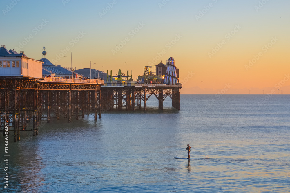 UK, Brighton, 11.1.2025: man on a board in sea at sunset UK, Brighton, 11.1.2025: man on a board in sea at sunset