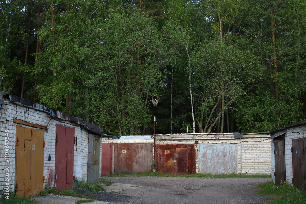 A long row of garages is situated with trees in the background A long row of garages is situated with trees in the background