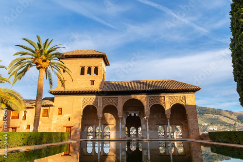 El Palacio del Partal  or Partal Palace in the Alhambra fortress complex, Granada, Andalusia, Spain. Moorish architecture. Courtyard with palms and pool. Reflection in water. Nasrid dynasty.