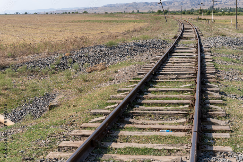 A train track with a grassy area in the background. The train tracks are old and rusty A train track with a grassy area in the background. The train tracks are old and rusty