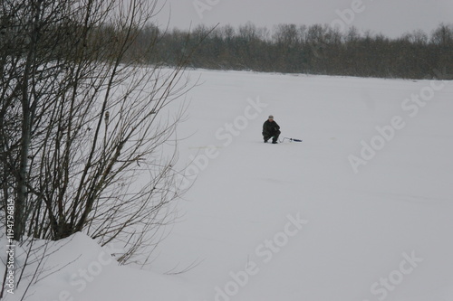 
fisherman catches fish in a hole on the river in winter photo