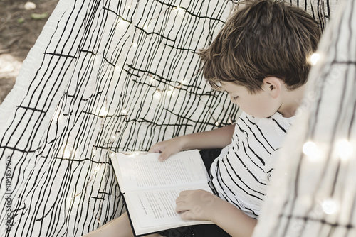 boy reading in treehouse hammock photo