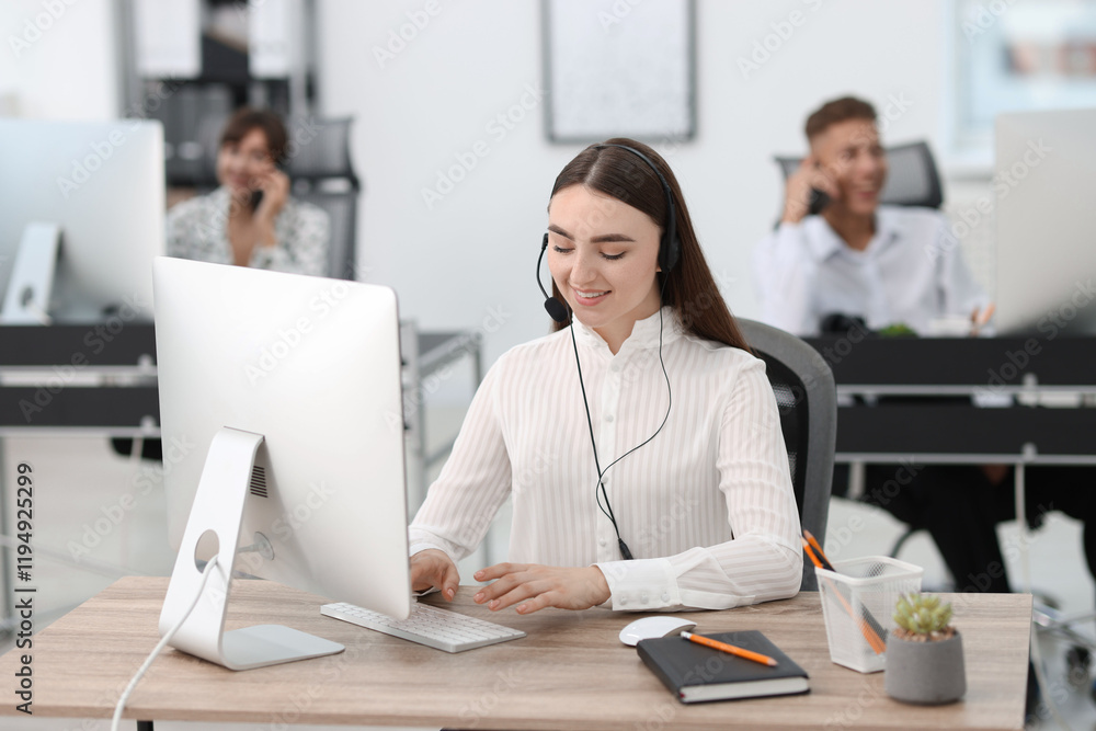 Saleswoman talking to client via headset at desk in office Saleswoman talking to client via headset at desk in office