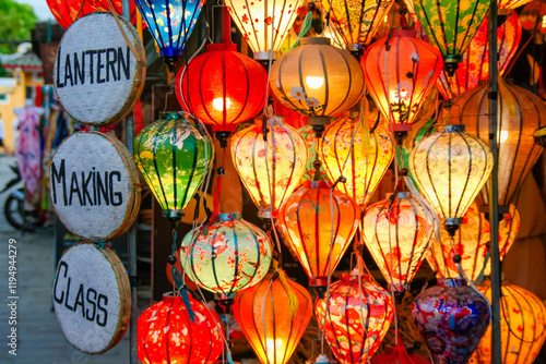 A sign that hangs on the side of a vibrant collection of lanterns that read Lantern making class in Hoi An Vietnam photo