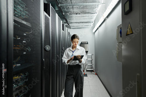 IT specialist in a white shirt focuses on her tasks in a sleek server room with advanced technology.